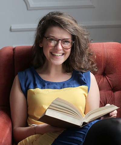 Testimonials woman in blue and yellow dress sitting on red sofa